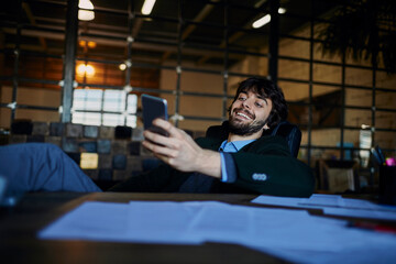 Young man taking a break from working in the office in a startup company and using a smart phone