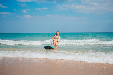 Fototapeta na wymiar Adorable teen girl on the beach having fun in shallow water playing with board