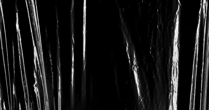 Explore the captivating visual landscape of a background textured with black crumpled and creased plastic, adding depth and character to any composition.