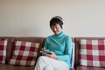 スマートフォンで音楽を聴くシニア女性
