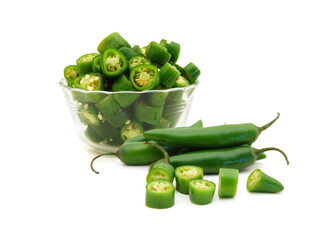 Bunch of fresh green chili peppers and some cut pieces in glass bowl on a white background