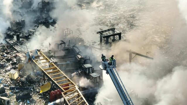 Aerial orbiting shot showing group of firefighter on ladder extinguish burning vehicles after gas explosion during sunny day