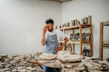 dizzy stone worker holding his forehead while standing in the warehouse