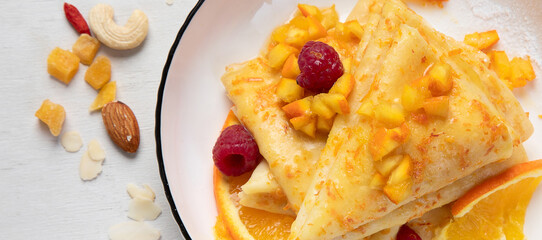 Crepe suzette with orange sauce and raspberry for a delicious breakfast.