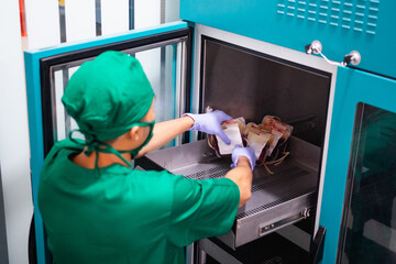 male hospital employee wearing uniform while storing blood bag in storage cabinet