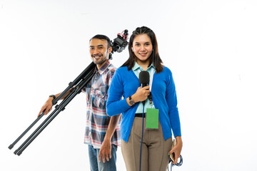 a female reporter in blue cardigan standing with the microphone at her hand with the cameraman standing behind bring one set of camera and smiling