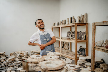 Asian businessman with an expression of back pain while holding his waist in a stone craft warehouse