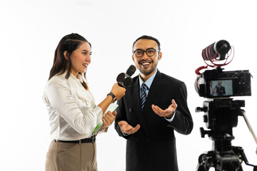 an adult men in black suit with eye glasses talking to the camera while interviewed by a beautiful journalist in white blouse