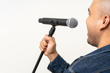 Fototapeta na wymiar Close up male hand holding High quality dynamic microphone and singing song or speaking talking with people on isolated white background. Male testing microphone voice for interview