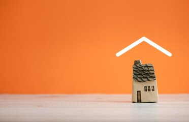isolated ceramic home model covered by roof icon on orange background