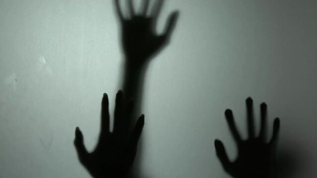 Abstract spooky defocused hand slow motion silhouettes of people behind mirror,