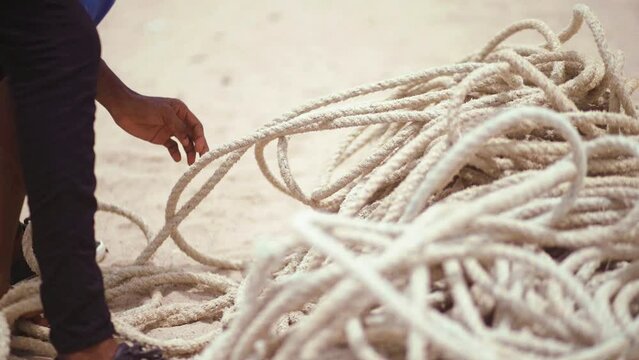 close up of unidentifiable Fisherman's hands gathering thick fishing ropes at shore
