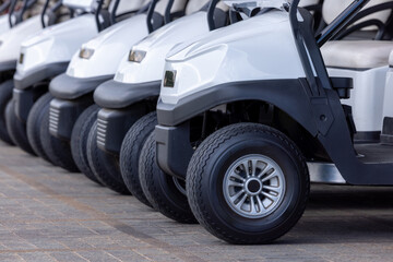  Golf cars in a row outdoors on a golf course. A row of empty golf carts on a golf course. golf course carts cars at luxury resort sport venue.All lined up ready for a tournament on a course.