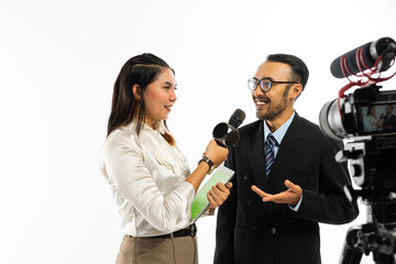 an adult men with eye glasses talking to the female journalist in white blouse using a black microphone and recorded by one set of camera
