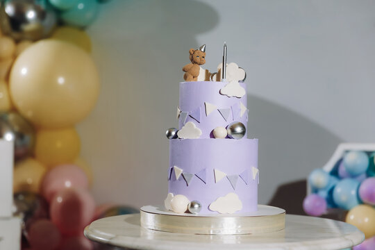 Cake on a background blue, gold, brown balloons for birthday party. Baby shower. Trendy Cake with a figure bear for boy. Celebration baptism concept. Delicious reception. Photo wall, arch with decor.