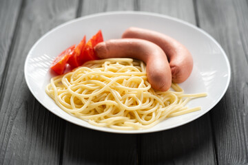 hot sausages with spaghetti in a plate, children's menu of a cafe or restaurant, close-up