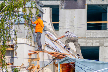 Construction workers repair the roof of the building on a summer day
