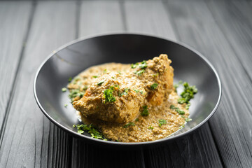 Close up view of chicken breast in creamy sauce in plate on black wooden background. Healthy diet food.