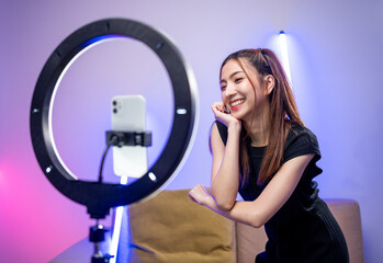 Young trendy influencer asian woman dancing on mobile phone at home in living room with neon light....