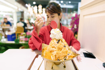 Happy woman eating shaved iced with Thai tea, bread and topping. Famous Dessert in Bangkok, Thailand - obrazy, fototapety, plakaty
