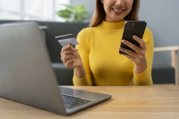 Asian businesswoman shopping online on mobile with credit card for convenient spending at home on...