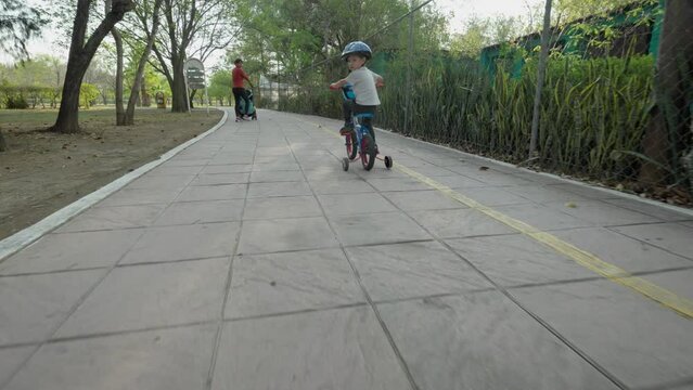 A little boy on a bike and his mom with a stroller taking a walk