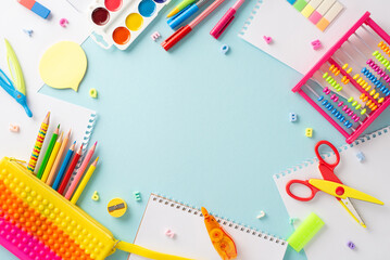 Discover the magic of education for small kids through this captivating top view photo: a charming display of colorful school supplies on an isolated pastel blue backdrop, ready for text or promotions