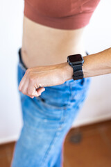 Close up girl in denim shorts looking at her watch.
