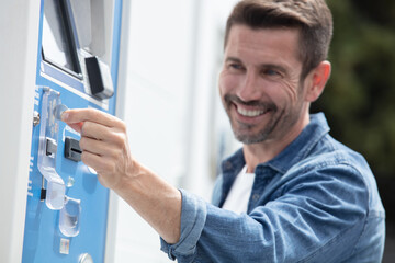 a happy man paying at parking meter