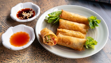 Crispy golden fried vegetable spring rolls with fresh ingredients served with soy and sweet and sour sauce in an oriental restaurant