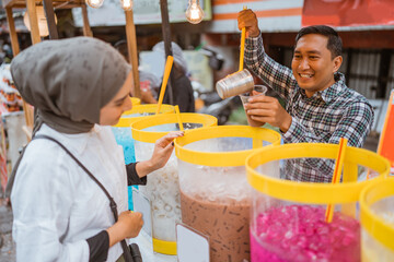 man sells colorful drink and juice in a jar to his female customer. street food vendor