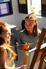 Obraz premium Happy diverse schoolchildren painting using brush and easel in school art class
