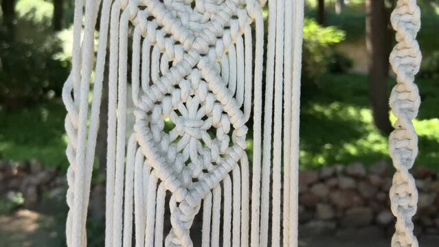Close up handmade woven cotton macrame decor in the green garden in the backyard of the house