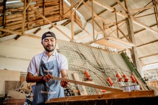 male carpenter checking the quality of wood materials before working in a wood craft workshop