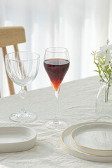 Wine glasses and white plates on white table.