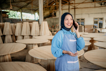 veiled businesswoman using a cellphone call to work at a woodcraft shop