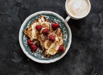 Delicious breakfast - cappuccino and peanut paste, banana, chocolate toast on a dark background, top view