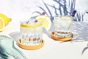 Chilled lavender lemonade with lemon and ice on a wooden stand on a gray table. Diet non-alcoholic...