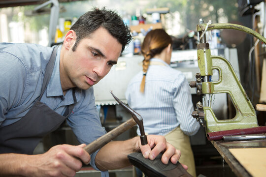 pciture of cobbler fixing a shoe sole - Powered by Adobe