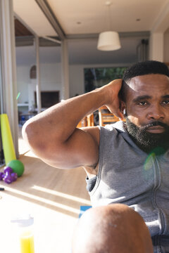 Portrait of focused african american man wearing sportswear and exercising on mat at home