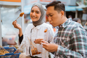 couple have fun enjoying snacks from street vendor shop during fasting in ramadan