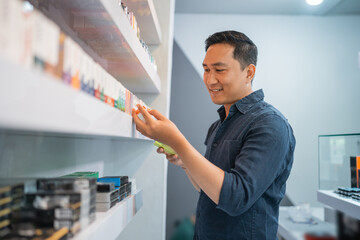 male seller observing the e liquid from the shelf at vape store