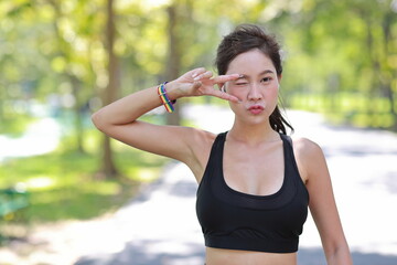 Young cheerful asian model transgender LGBT with wristband showing victory symbol while smiling and looking at camera. Photo of attractive sporty woman runner in sportswear. pride and equality concept