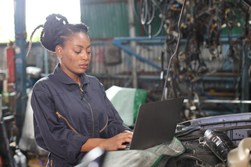 Woman technician car mechanic in uniform checking maintenance a car service with computer at repair...