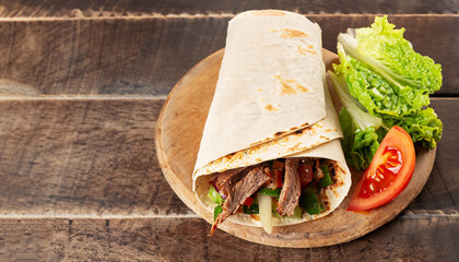 Panorama banner with spicy Turkish doner kebab filled with flaked spit roasted meat and fresh salad...