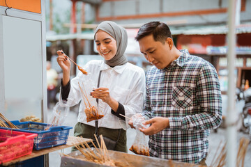 couple have fun enjoying snacks from street vendor shop during fasting in ramadan