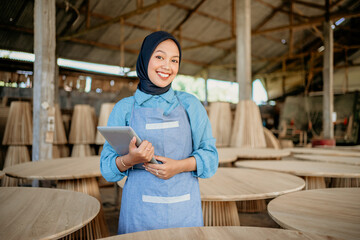 smiling woman in veil with holding a tablet in wood craft store