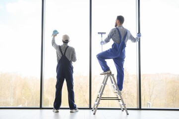 back view of multicultural professional workers washing large panoramic windows in office