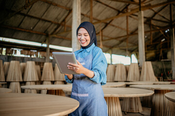 young businesswoman in veil standing using a tablet to work in wood craft shop