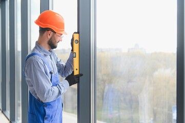 The foreman installs a window frame in the room